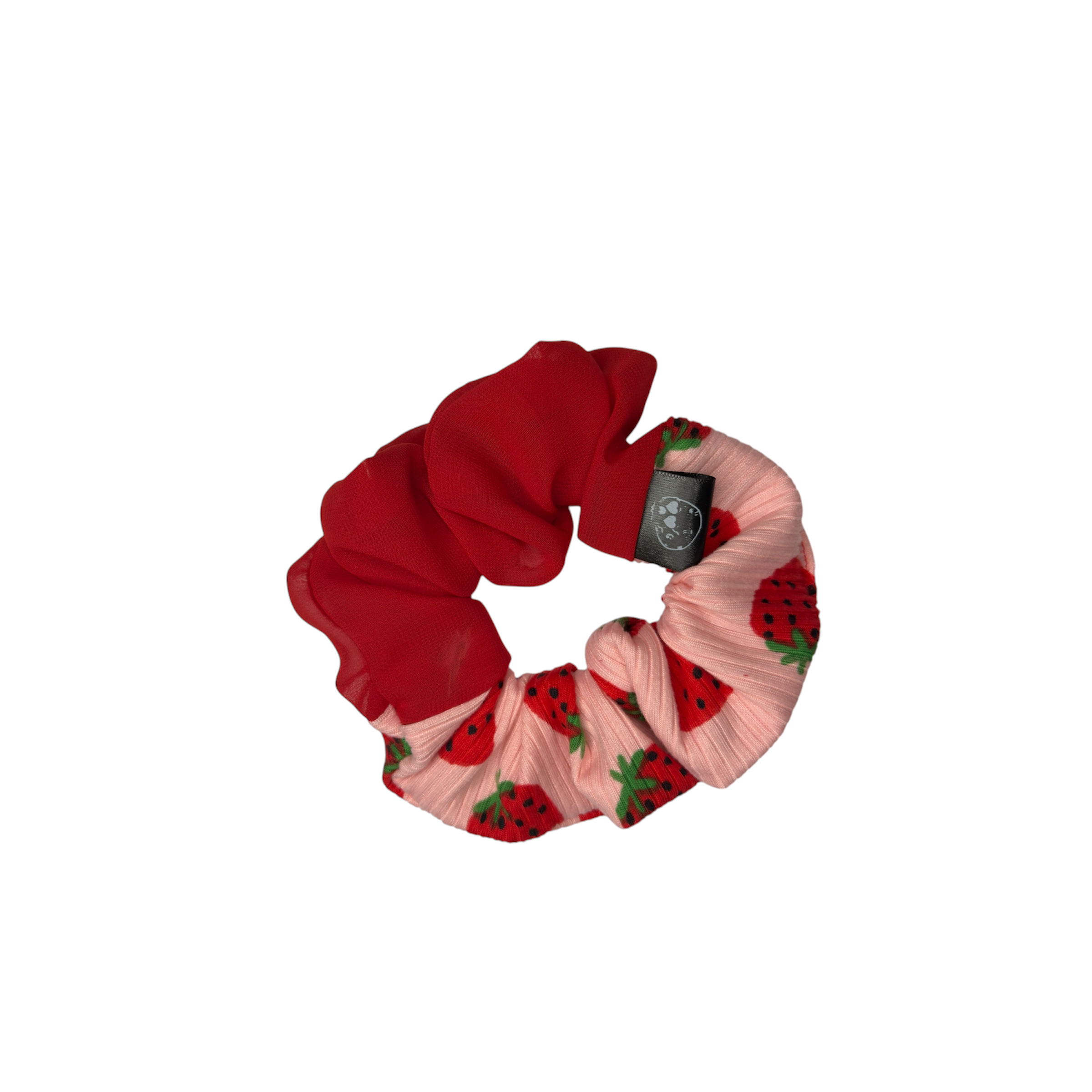 A fabric hair scrunchie featuring a solid red section and a pleated light pink section with a strawberry pattern, complete with the black Atila brand tag.